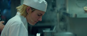 Movie still from “Burnt” (2015), directed by John Wells – A woman wearing a chef's hat in a kitchen; Close Up shot, Low angle