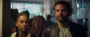 Movie still from “Burnt” (2015), directed by John Wells – A man standing next to a woman with dreadlocks in a room; Close Up shot, Over the shoulder angle