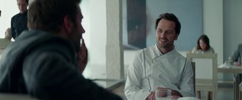 Movie still from “Burnt” (2015), directed by John Wells – A man in a chef's outfit talking to another man; Close Up shot, Over the shoulder angle