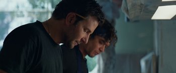 Movie still from “Burnt” (2015), directed by John Wells – A couple of men standing next to each other in a room; Close Up shot, Low angle