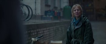 Movie still from “Burnt” (2015), directed by John Wells – A woman standing next to a bicycle on the side of the road; Close Up shot, Over the shoulder angle