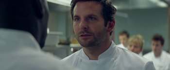 Movie still from “Burnt” (2015), directed by John Wells – A person wearing a chef's outfit; Close Up shot, Over the shoulder angle