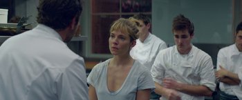 Movie still from “Burnt” (2015), directed by John Wells – A woman in a white shirt is looking at a man; Close Up shot, Over the shoulder angle