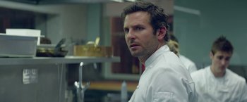 Movie still from “Burnt” (2015), directed by John Wells – A person wearing a white shirt; Close Up shot, Over the shoulder angle