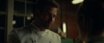 Movie still from “Burnt” (2015), directed by John Wells – A man wearing a chef's outfit in a kitchen; Close Up shot, Low angle