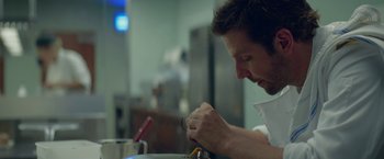 Movie still from “Burnt” (2015), directed by John Wells – A man in white shirt holding a screwdriver in a kitchen; Close Up shot, Low angle