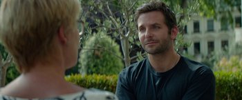 Movie still from “Burnt” (2015), directed by John Wells – A man and a woman are sitting in front of a tree; Close Up shot, Over the shoulder angle