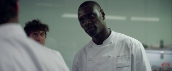 Movie still from “Burnt” (2015), directed by John Wells – A man in a chef's outfit standing in front of a mirror; Close Up shot, Over the shoulder angle