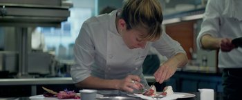 Movie still from “Burnt” (2015), directed by John Wells – A woman in a chef's outfit cutting a piece of cake; Close Up shot, Low angle