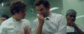 Movie still from “Burnt” (2015), directed by John Wells – A man in a chef's outfit holding a spoon; Close Up shot, Over the shoulder angle