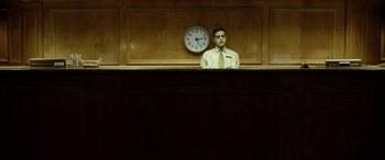 A man sitting in front of a clock in a room