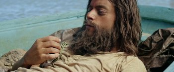 A bearded man holding a snake in his hand