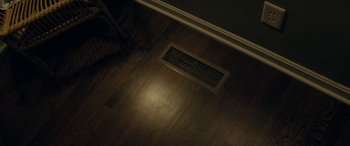 Movie still from “By Night's End” (2020), directed by Walker Whited – A floor vent on a hard wood floor in a room; Extreme Close Up shot, High angle