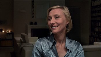 Movie still from “Caché” (2005), directed by Michael Haneke – A woman with short blonde hair smiling for the camera; Close Up shot, Over the shoulder angle
