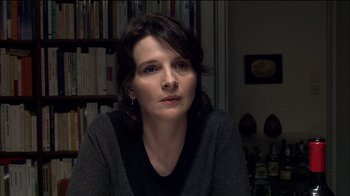 Movie still from “Caché” (2005), directed by Michael Haneke – A person sitting in front of a book shelf; Close Up shot, Over the shoulder angle