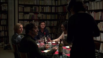 Movie still from “Caché” (2005), directed by Michael Haneke – A group of people sitting at a table with wine glasses; Medium shot, Over the shoulder angle