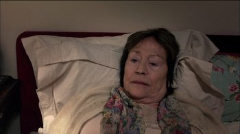 Movie still from “Caché” (2005), directed by Michael Haneke – An older woman laying in a bed with her eyes closed; Close Up shot, High angle