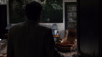 Movie still from “Caché” (2005), directed by Michael Haneke – A man sitting in a chair in front of a window; Wide shot, Over the shoulder angle