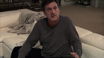 Movie still from “Caché” (2005), directed by Michael Haneke – A person sitting on a bed; Medium shot, High angle