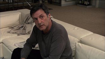 Movie still from “Caché” (2005), directed by Michael Haneke – A person sitting on a couch; Medium shot, High angle