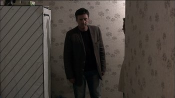 Movie still from “Caché” (2005), directed by Michael Haneke – A man standing in front of a mirror in a room; Medium shot, Over the shoulder angle