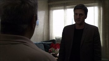 Movie still from “Caché” (2005), directed by Michael Haneke – A man standing in front of a mirror talking to another man in front of a window; Medium shot, Over the shoulder angle