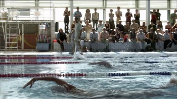 Movie still from “Caché” (2005), directed by Michael Haneke – A group of people swimming in a pool with spectators watching; Extreme Wide shot, High angle