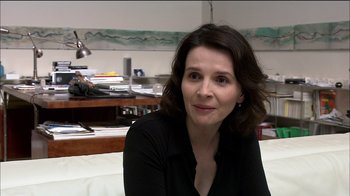 Movie still from “Caché” (2005), directed by Michael Haneke – A person sitting on a couch in a room; Close Up shot, Over the shoulder angle