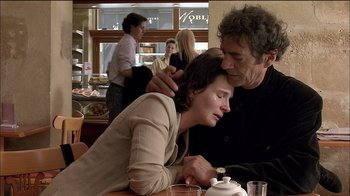 Movie still from “Caché” (2005), directed by Michael Haneke – A man and a woman sitting at a table in front of a coffee pot; Medium shot, Over the shoulder angle