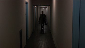 Movie still from “Caché” (2005), directed by Michael Haneke – A man walking down a long hallway in a building; Wide shot, High angle