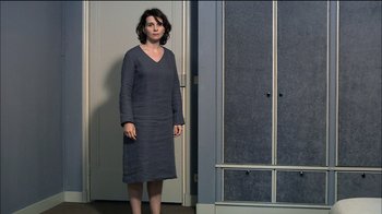 Movie still from “Caché” (2005), directed by Michael Haneke – A woman standing in front of a door wearing a gray dress; Wide shot, High angle