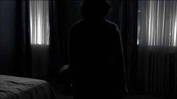 Movie still from “Caché” (2005), directed by Michael Haneke – A person standing in a dark room in front of a window; Wide shot, Over the shoulder angle