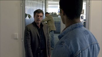 Movie still from “Caché” (2005), directed by Michael Haneke – A man in a brown jacket is looking at another man in a blue shirt; Medium shot, Over the shoulder angle