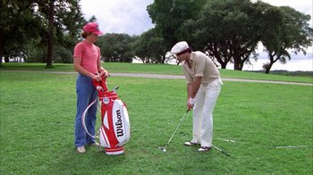 Movie still from “Caddyshack” (1980), directed by Harold Ramis – Two people are playing golf in a park; Wide shot, Low angle