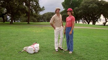 Movie still from “Caddyshack” (1980), directed by Harold Ramis – Two men standing in a field with a golf bag; Wide shot, Low angle