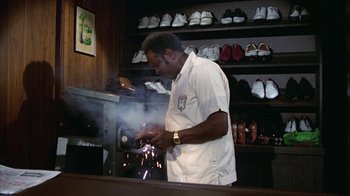 Movie still from “Caddyshack” (1980), directed by Harold Ramis – A man in a white shirt is working in a shoe store; Medium shot, Low angle