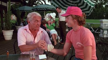Movie still from “Caddyshack” (1980), directed by Harold Ramis – A man and a woman shake hands at an outdoor table; Medium shot, Low angle
