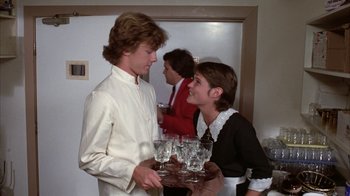 Movie still from “Caddyshack” (1980), directed by Harold Ramis – A man and a woman holding a tray of wine glasses; Medium shot, Over the shoulder angle