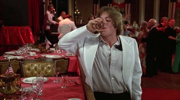 Movie still from “Caddyshack” (1980), directed by Harold Ramis – A man in a white jacket drinking from a wine glass; Medium shot, Low angle