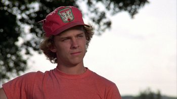 Movie still from “Caddyshack” (1980), directed by Harold Ramis – A young man wearing a red hat and a red t - shirt; Close Up shot, Low angle