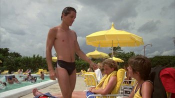 Movie still from “Caddyshack” (1980), directed by Harold Ramis – A man in a black swim suit standing next to a woman in a yellow bathing suit; Medium shot, Low angle