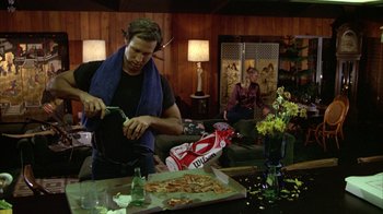 Movie still from “Caddyshack” (1980), directed by Harold Ramis – A man cutting a pizza with a knife and fork; Medium shot, Low angle