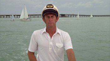 Movie still from “Caddyshack” (1980), directed by Harold Ramis – A man in a sailor's hat standing in front of a body of water; Medium shot, Low angle