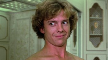 Movie still from “Caddyshack” (1980), directed by Harold Ramis – A young man with long blonde hair is smiling for the camera; Close Up shot, Low angle