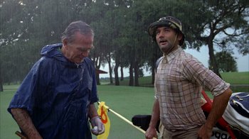 Movie still from “Caddyshack” (1980), directed by Harold Ramis – Two men are playing golf on a rainy day; Medium shot, Low angle