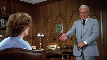 Movie still from “Caddyshack” (1980), directed by Harold Ramis – An older man in a gray suit talking to a young man in a blue suit; Medium shot, Over the shoulder angle
