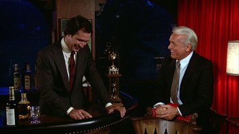 Movie still from “Caddyshack” (1980), directed by Harold Ramis – A man in a suit and tie and another man in a suit and tie; Medium shot, Over the shoulder angle