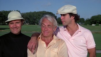 Movie still from “Caddyshack” (1980), directed by Harold Ramis – Two men and an older man are posing for a picture; Close Up shot, Low angle