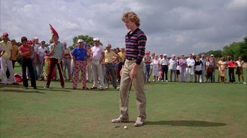 Movie still from “Caddyshack” (1980), directed by Harold Ramis – A man standing on top of a golf course holding a golf club; Wide shot, Low angle