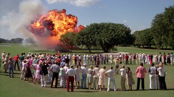 Movie still from “Caddyshack” (1980), directed by Harold Ramis – A group of people standing in a field watching a fire explode; Extreme Wide shot, High angle